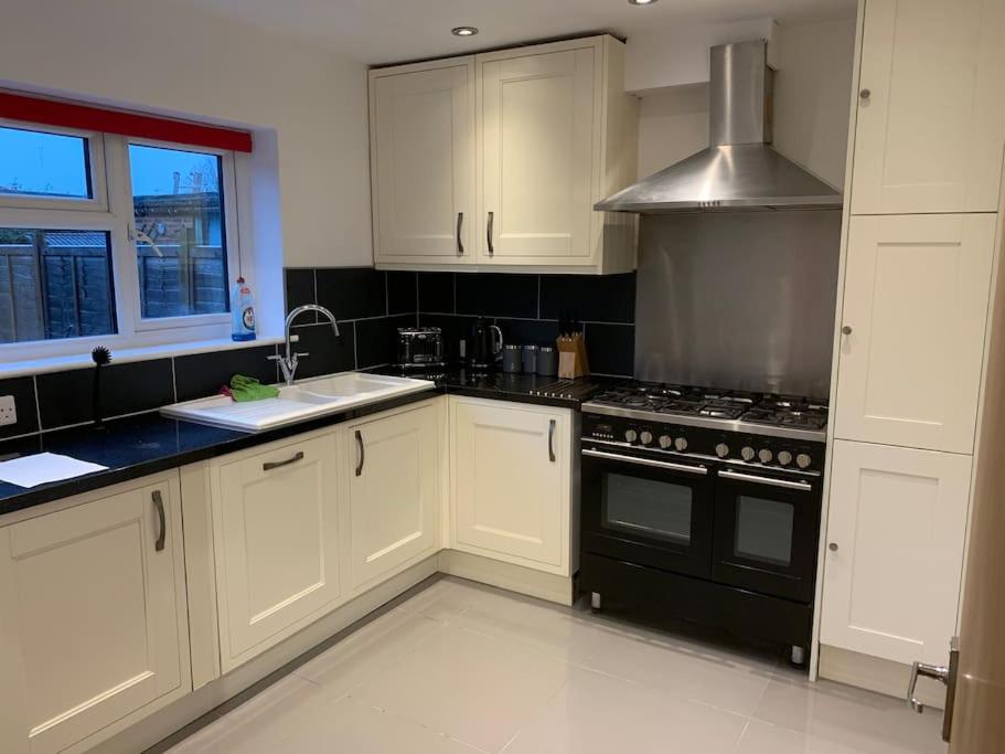 a kitchen with white cabinets and a black stove top oven at Fabulous 4 bed 4 bath right by Luton Airport in Luton
