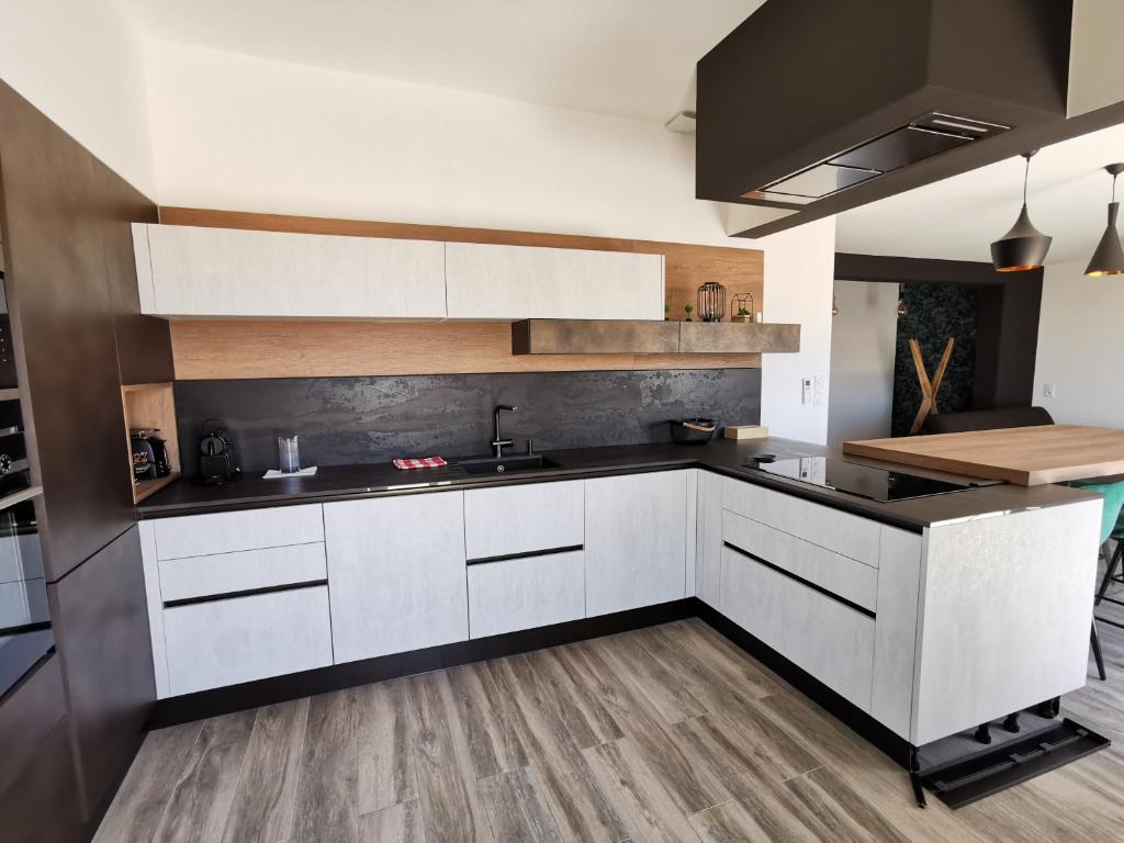 eine Küche mit weißen Schränken und schwarzen Arbeitsplatten in der Unterkunft AS22351 - P3 au 2ème et dernier étage dans une résidence neuve en Centre Ville in Le Grau-du-Roi