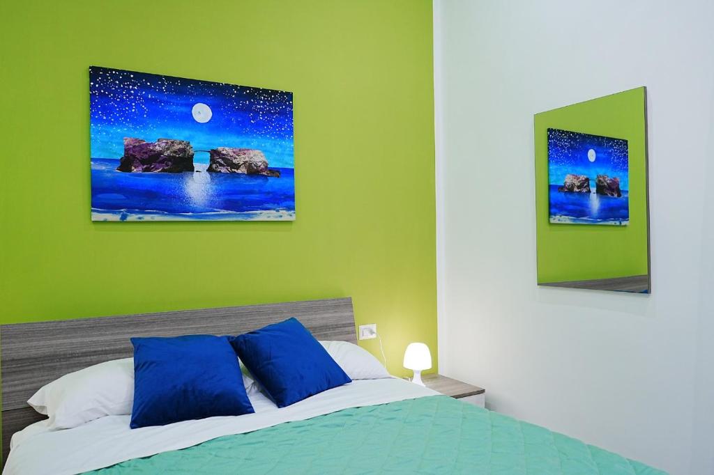 een bed met blauwe kussens in een groene slaapkamer bij Just Like Home in Napels