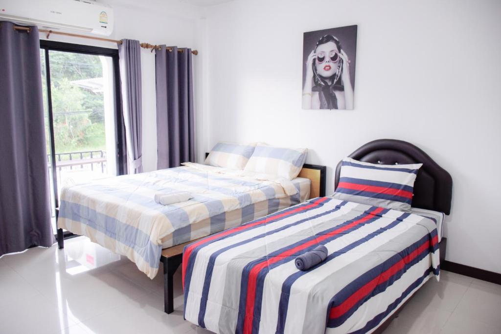 a bedroom with two beds and a picture of a dog at นอน นี่ นะ โฮสเทล Noen nee Na Hostel in Ban Non Na Yao