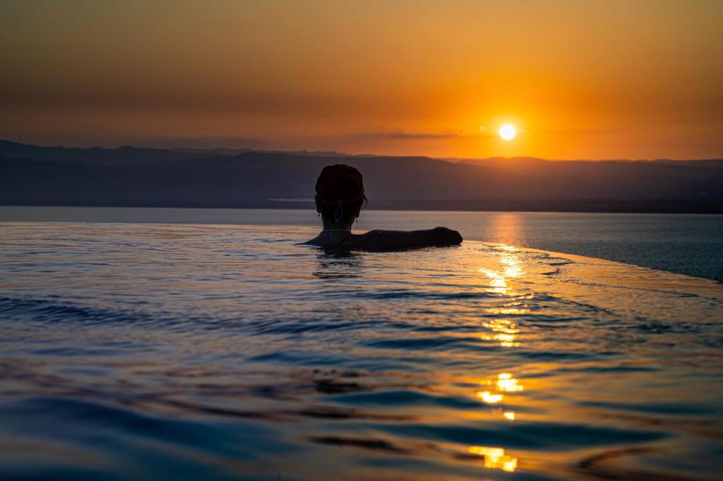 une personne nageant dans l'eau au coucher du soleil dans l'établissement Sunset apartment in Samarah Dead Sea resort, à Sowayma