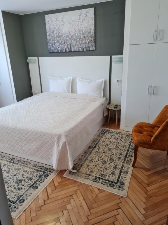 a bedroom with a white bed and a chair at Apartament Central in Gherla