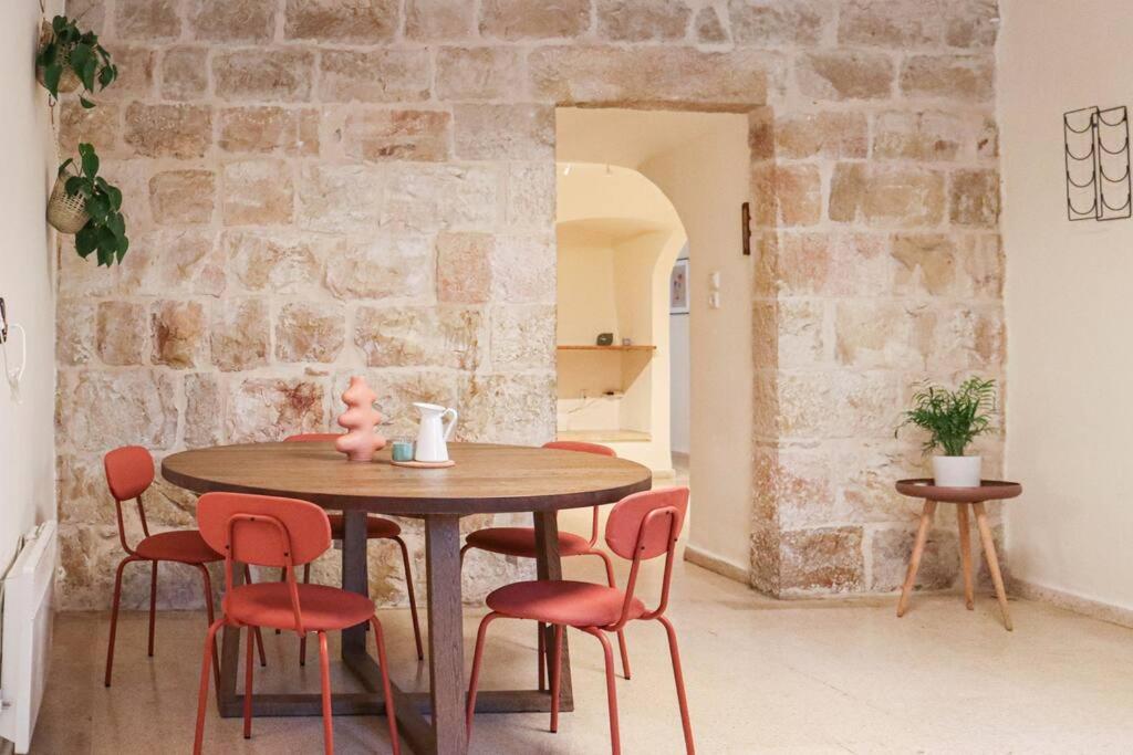 - une table et des chaises dans une pièce dotée d'un mur en pierre dans l'établissement Charming Jerusalem Home, à Jérusalem