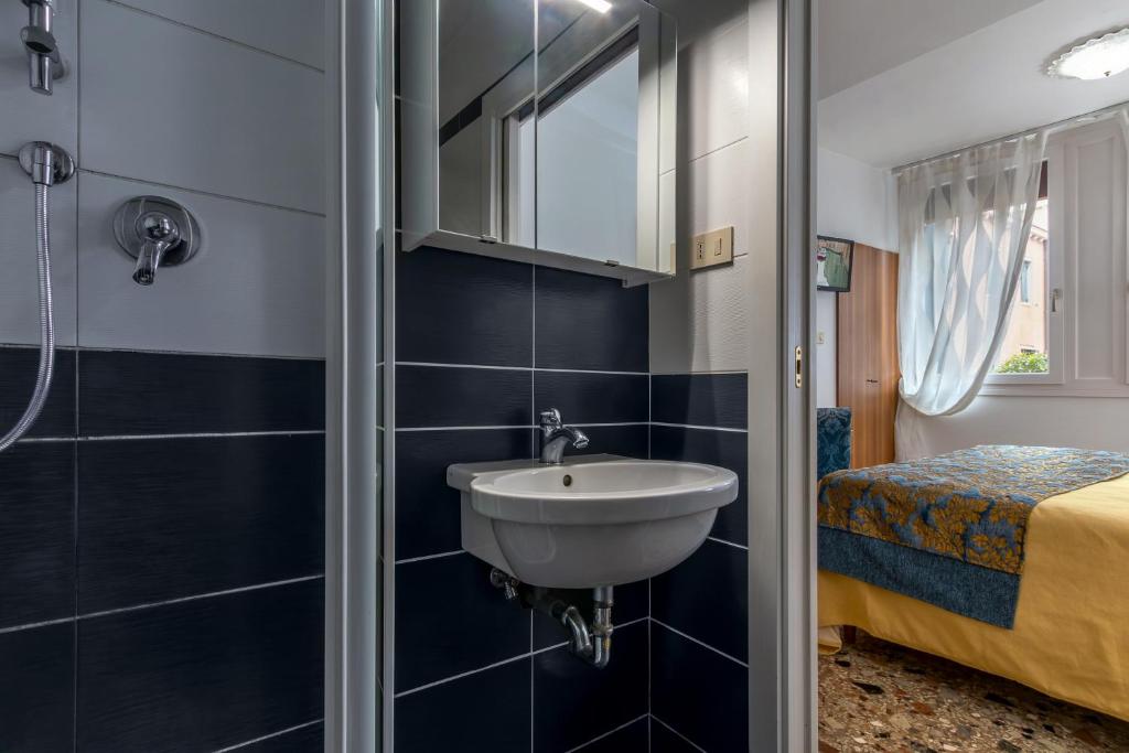 a bathroom with a sink and a bed at Hotel Casa Boccassini in Venice