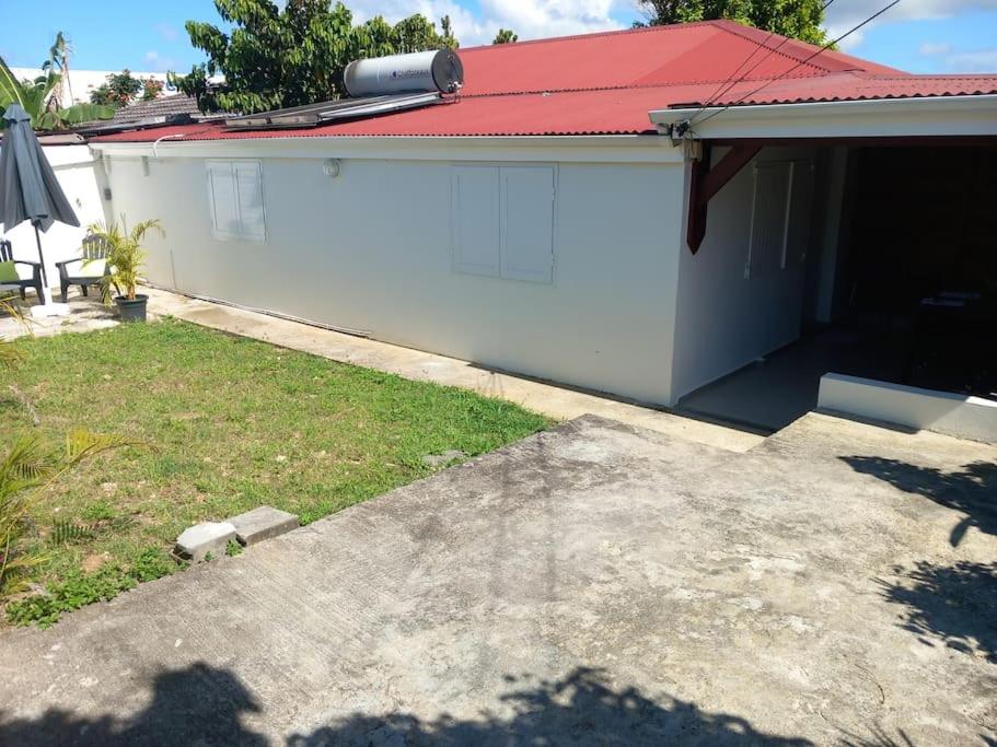 une maison blanche avec un toit rouge et une cour dans l'établissement Beau T2 Cosy tout Confort avec terrasse et jardin, à Les Abymes