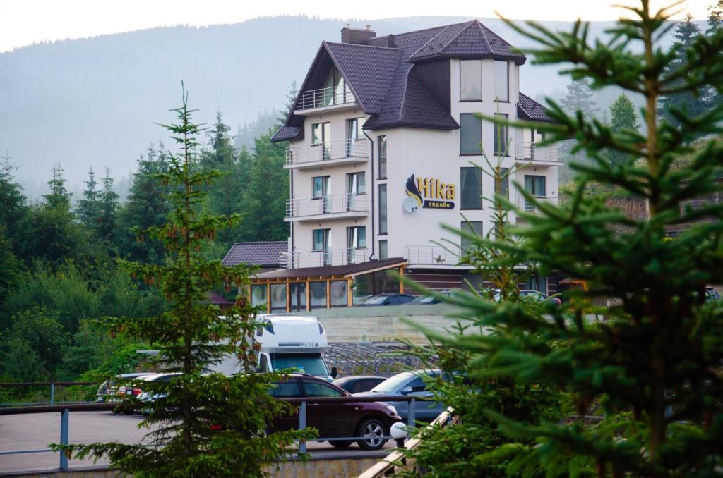 un gran edificio con coches estacionados en un estacionamiento en Ніка, en Bukovel