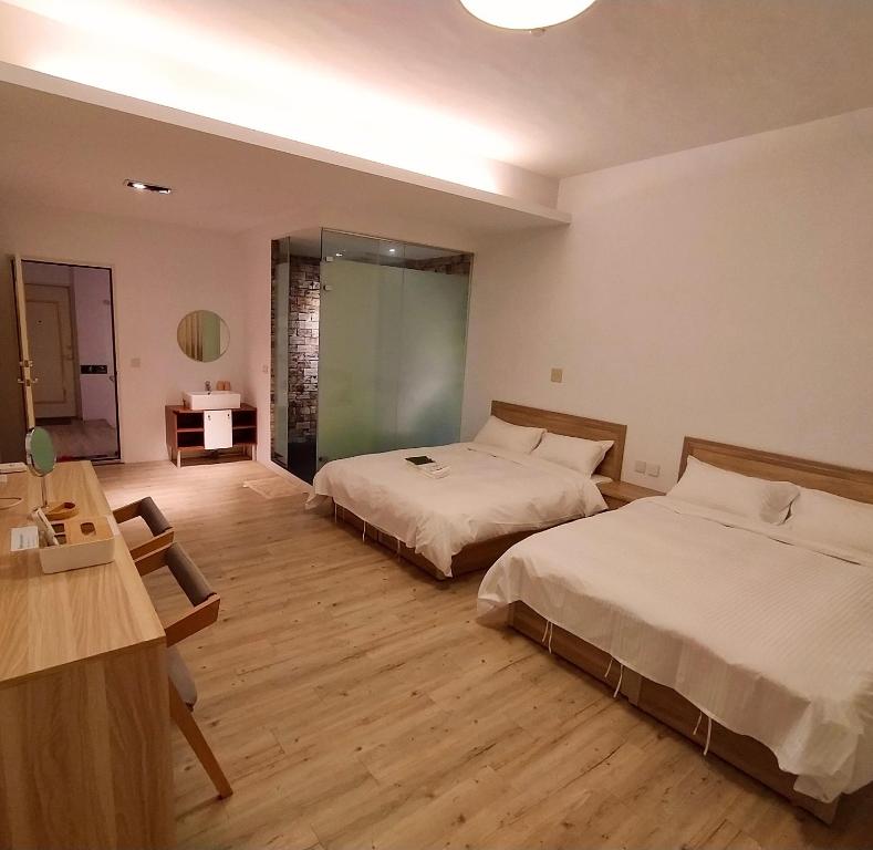 a hotel room with two beds and a table and a desk at Travel Life 源旅生活民宿 in Shuili