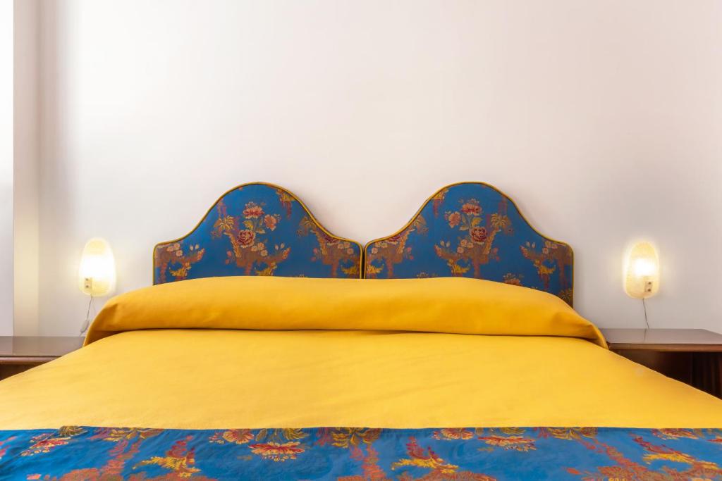 a bed with a blue headboard and a yellow blanket at Hotel Casa Boccassini in Venice