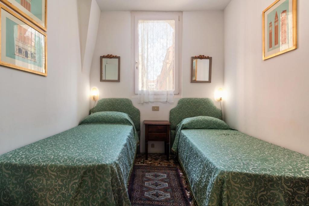 a room with four green beds and a window at Hotel Casa Boccassini in Venice