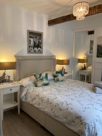 - une chambre avec un lit, deux tables et un lustre dans l'établissement Sommersway Cottage, à Brixham