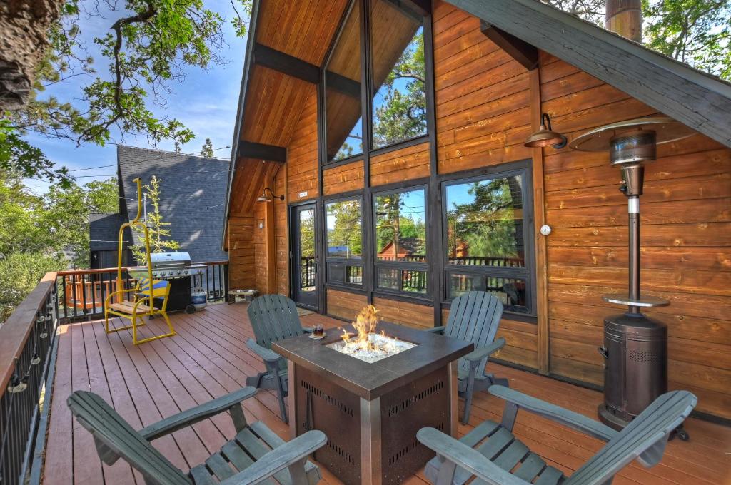 a cabin with a deck with a fireplace and chairs at New!!! Dreamy Bear Haus- Updated Retro Retreat & Spa, Pet & Kid Friendly in Big Bear Lake