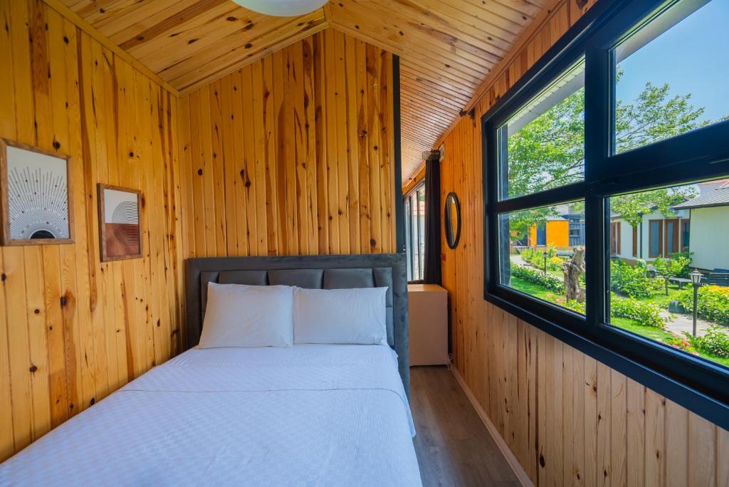 een bed in een houten kamer met 2 ramen bij İNCİ BOUTİQUE APART in Bodrum City