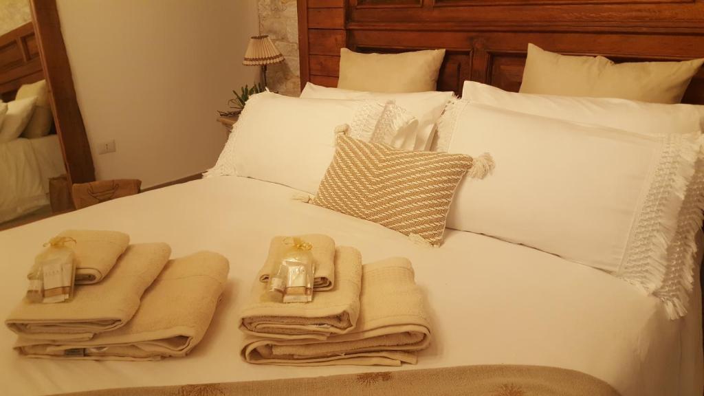 Una cama blanca con toallas y velas. en Il Rifugio dell'Aspide, en Roccadaspide