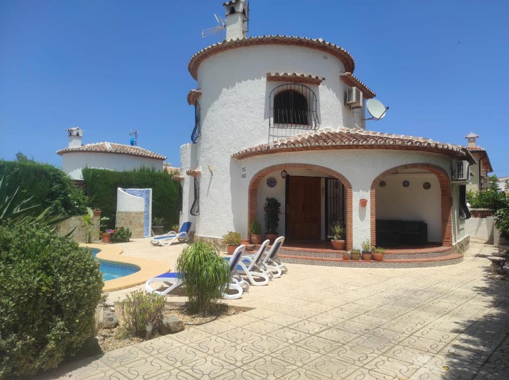 eine Villa mit einem Pool und Stühlen davor in der Unterkunft Villa Regina in Els Poblets in Els Poblets