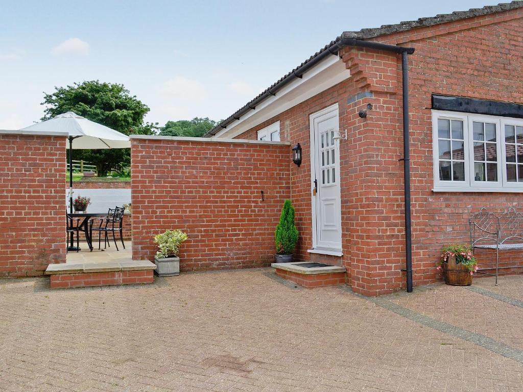 a brick house with a white door and a patio at Burghley Barn - Uk44744 in Tetford