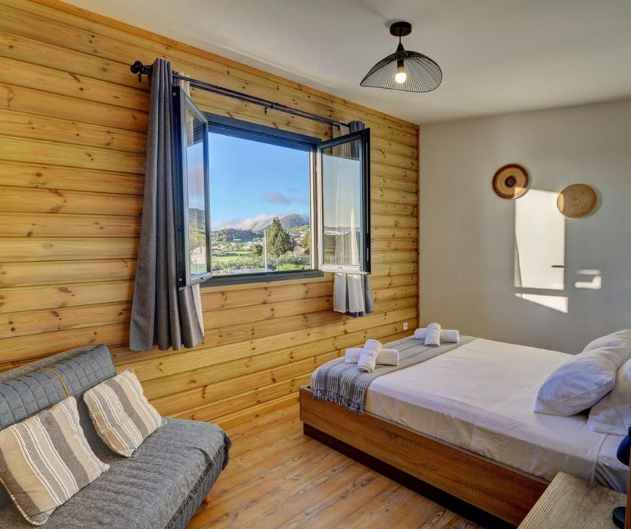 ein Schlafzimmer mit einem Bett, einem Fenster und einem Sofa in der Unterkunft L'INSTANT D'EVASION 2 Plaine des Cafres in La Plaine des Cafres