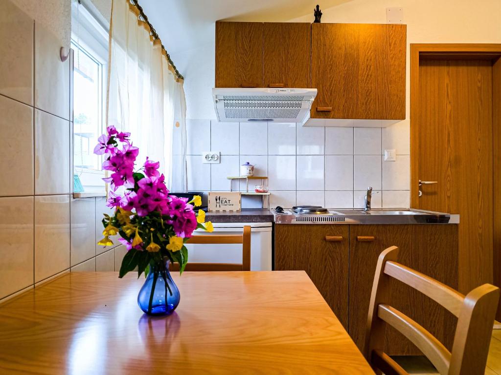 een vaas met bloemen op een houten tafel in een keuken bij Apartments Mani in Trogir