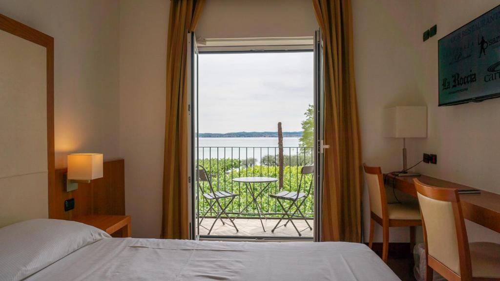 a bedroom with a bed and a view of a balcony at Hotel Mavino in Sirmione