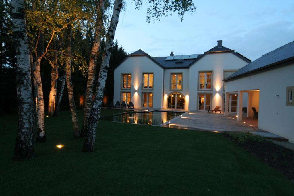 una casa con piscina por la noche en B&B White Pearl, en Müllerthal