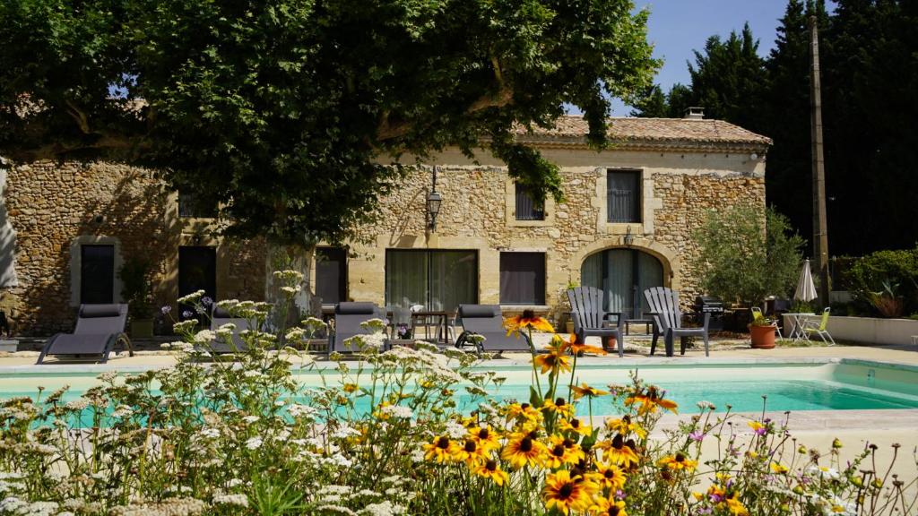 dom z basenem i kwiatami przed nim w obiekcie Mas Provençal typique récemment rénové w mieście Jonquières