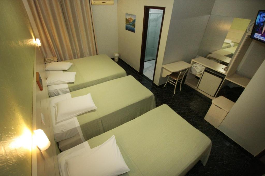 a hotel room with four beds and a mirror at Hotel Três Fronteiras in Foz do Iguaçu