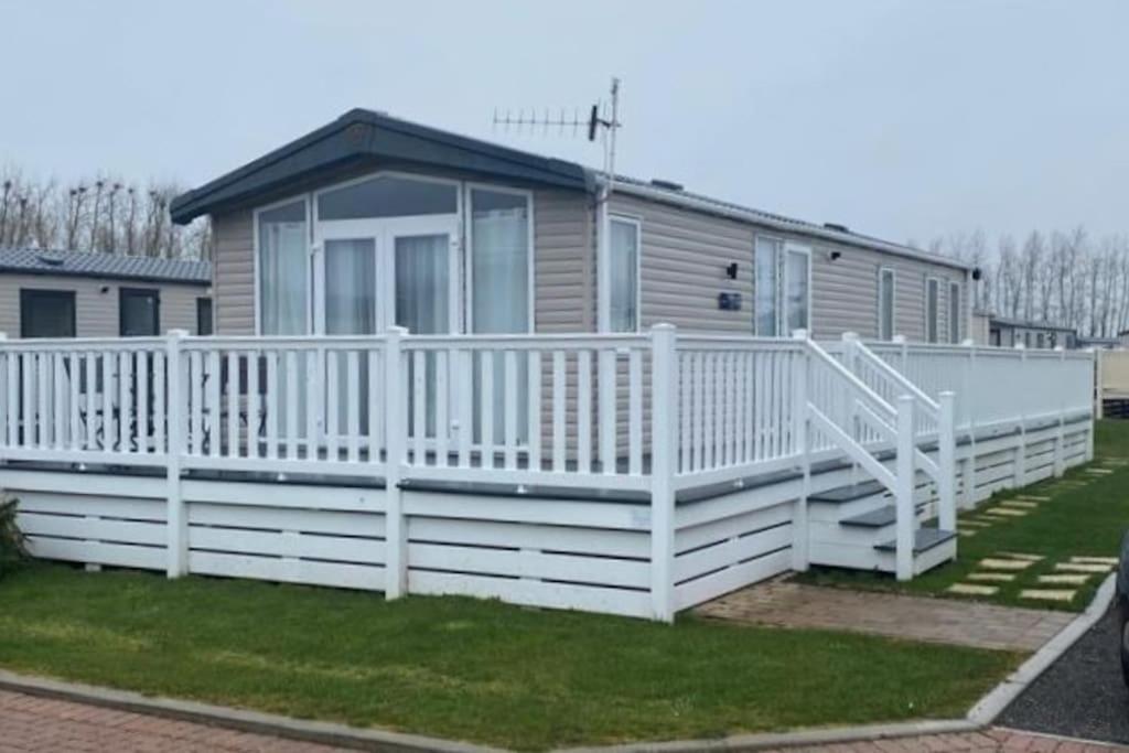 a house with a white porch and a white railing at Riverwood Lodge, The Boulevard, Seal Bay, Selsey in Selsey