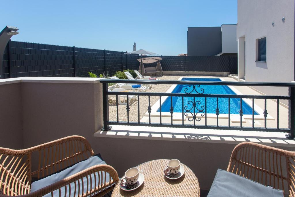 uma varanda com uma mesa e cadeiras e uma piscina em Modern apartment with swimming pool em Kaštela