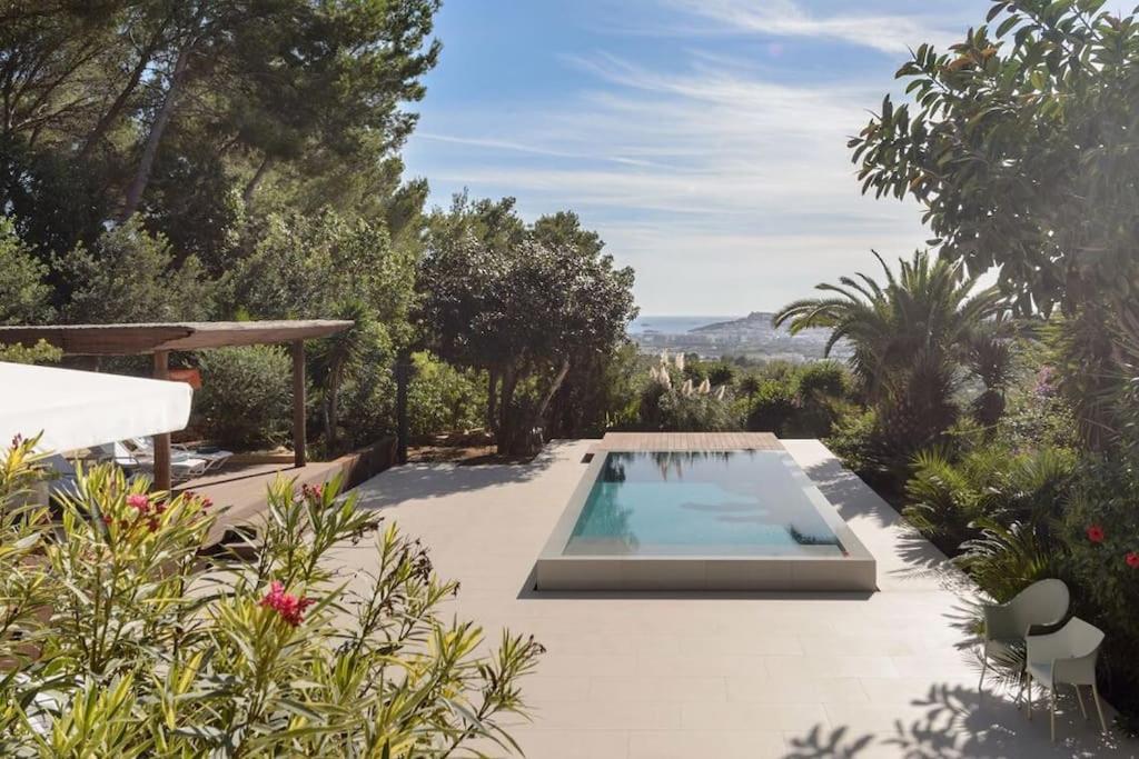 a swimming pool in the middle of a garden at Mordern Villa - Sea view - Near Eivissa old town in Can Furnet