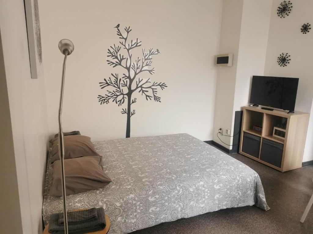 a bedroom with a bed with a tree on the wall at Impasse 1 in Fosses-La-Ville