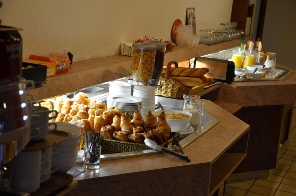 a breakfast buffet with pastries and croissants on a counter at The Originals City, Hôtel Amys, Tarbes Sud (Inter-Hotel) in Odos