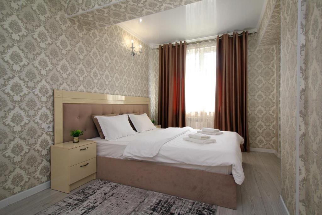 a bedroom with a large bed and a window at Your Home Away from Home in Almaty