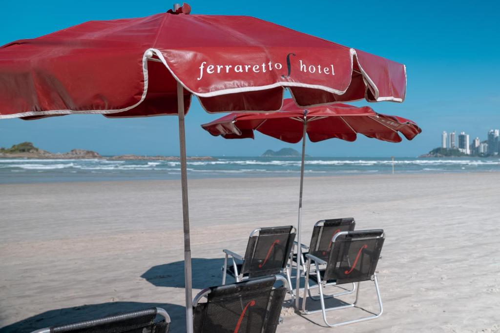 two chairs under an umbrella on the beach at Ferraretto Guarujá Hotel & Spa in Guarujá