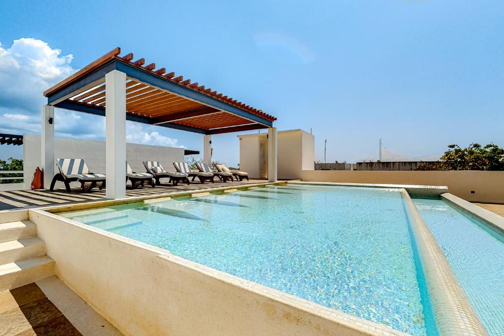 a swimming pool with chairs and a gazebo at La Selva 303 Sirenis in Akumal