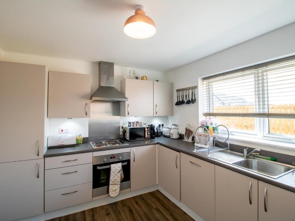 a kitchen with white cabinets and a sink at Pass the Keys Stunning Newcastle Home in Elswick