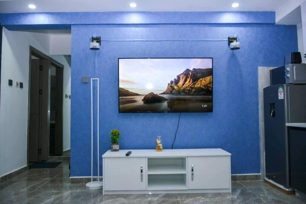 a room with a blue wall with a tv on it at Lovely instantworthy Premier One Bedroom Apartment in Nairobi