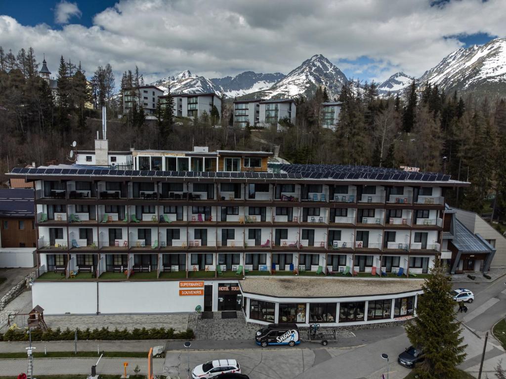 a large hotel with mountains in the background at Hotel Toliar in Vysoke Tatry - Strbske Pleso