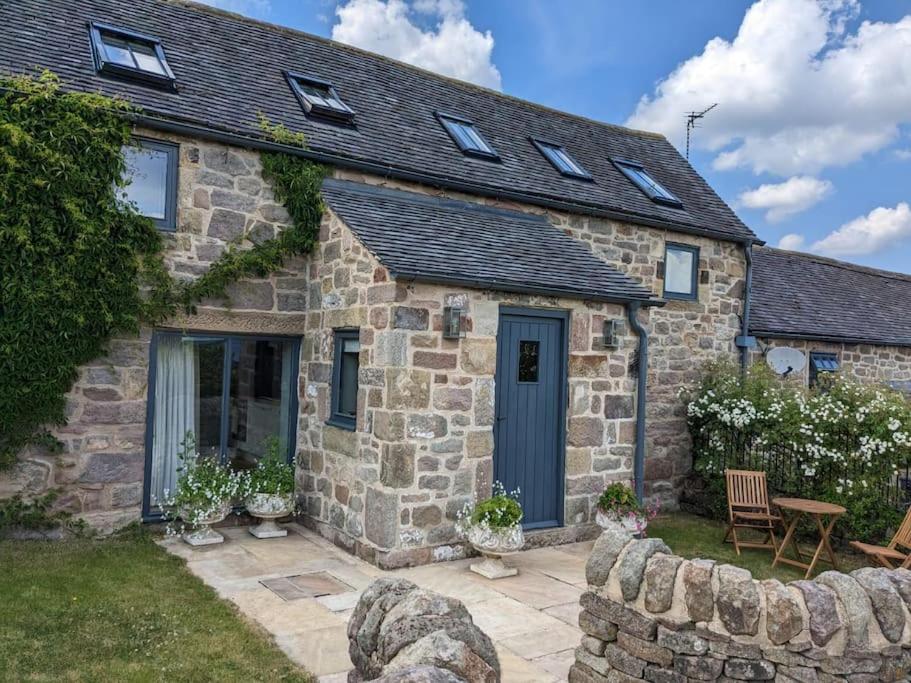 a stone house with a blue door and a patio at Cottage in Matlock, Derbyshire. Lower Holly Barn in Matlock Bank