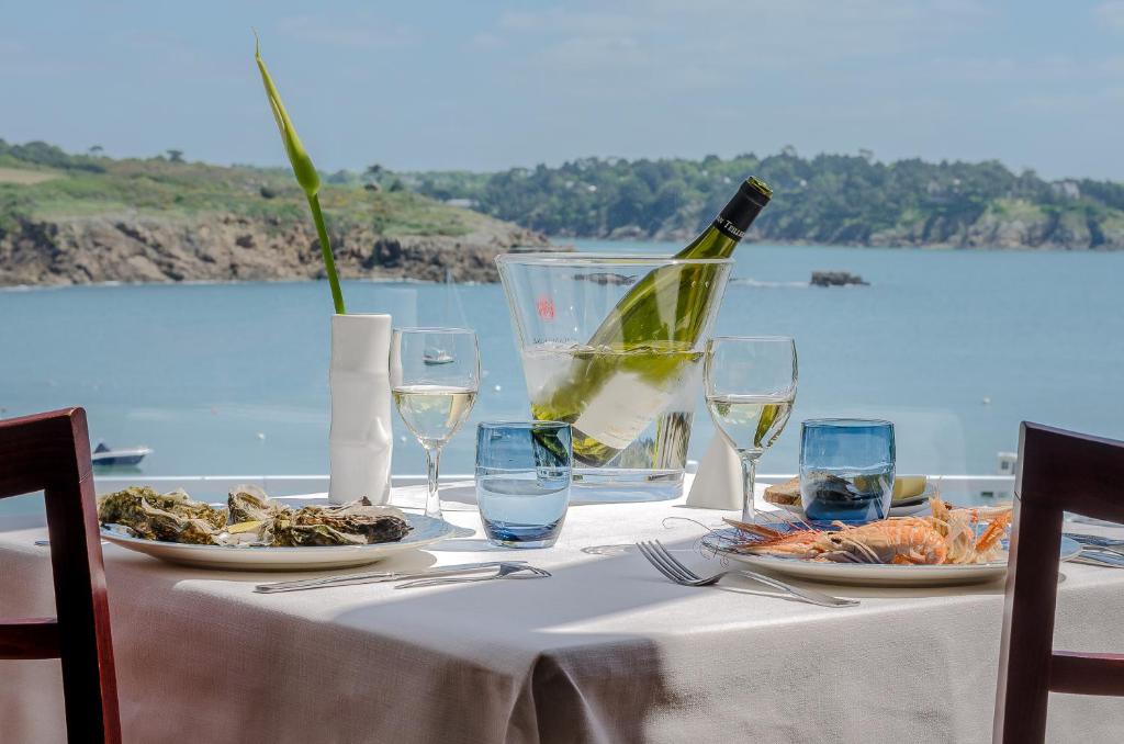 a table with a bottle of wine and plates of food at Hôtel Du Port Et De L'aven in Névez