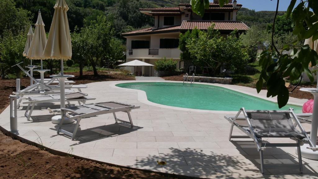 a swimming pool with chairs and umbrellas next to a house at Casa Vacanze Korello in Gasponi
