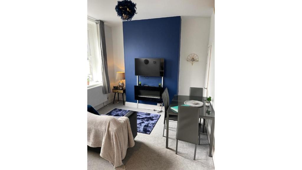 巴克斯頓的住宿－Torr Mews，客厅设有蓝色的墙壁和桌子