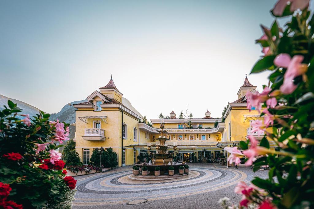 duży żółty budynek z fontanną przed nim w obiekcie Wellnessresidenz Alpenrose w mieście Maurach