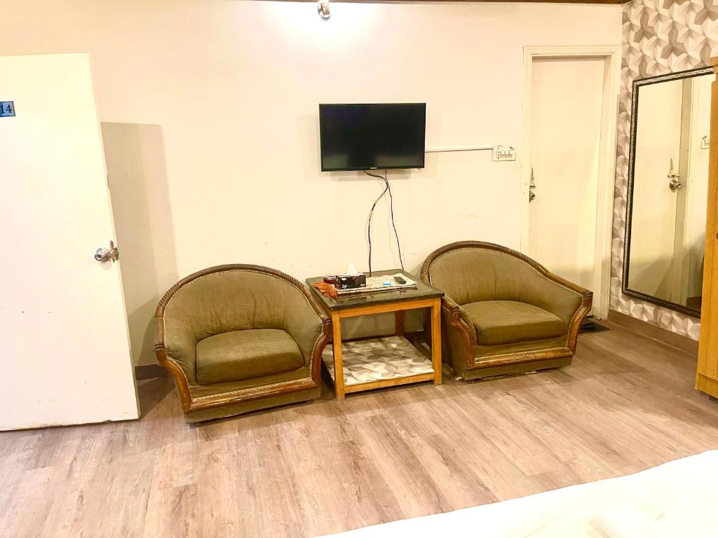 two chairs and a table in a room with a tv at Rehaish Inn in Karachi