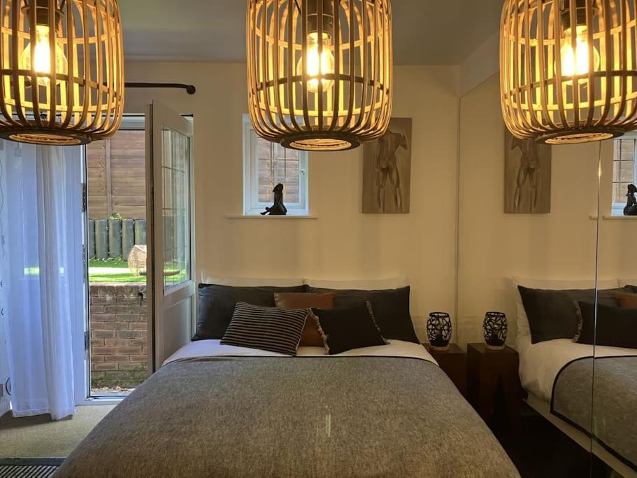 a bedroom with two beds and two chandeliers at The Studio in the Annex in Potters Bar