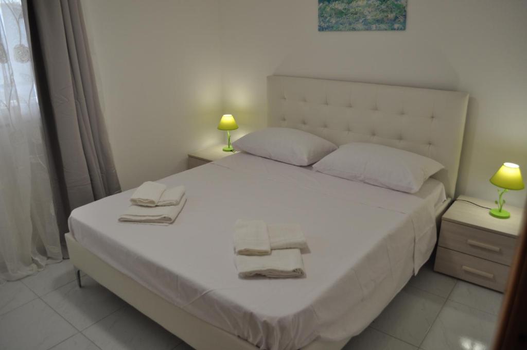een slaapkamer met een wit bed en handdoeken bij LECCE AL MARE in San Cataldo
