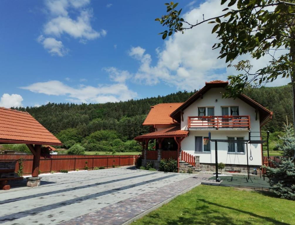 a house with a red roof and a patio at Dió vendégház in Praid