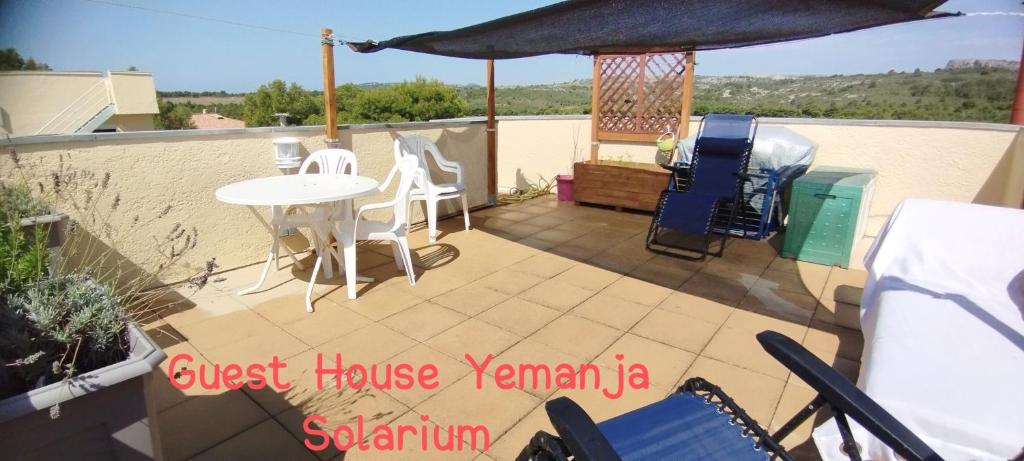 une terrasse avec une table, des chaises et un parasol dans l'établissement Guest House Yemanja, à Narbonne