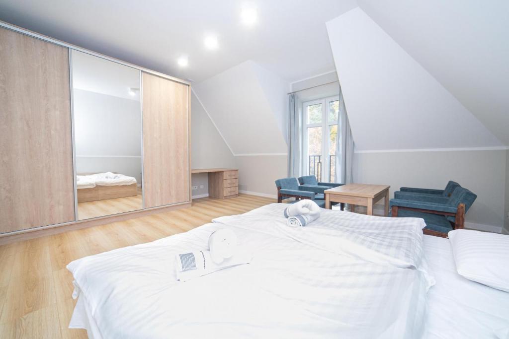 sypialnia z białym łóżkiem i dużym lustrem w obiekcie VacationClub - Zdrojowa 7 Apartament 10 w mieście Duszniki Zdrój