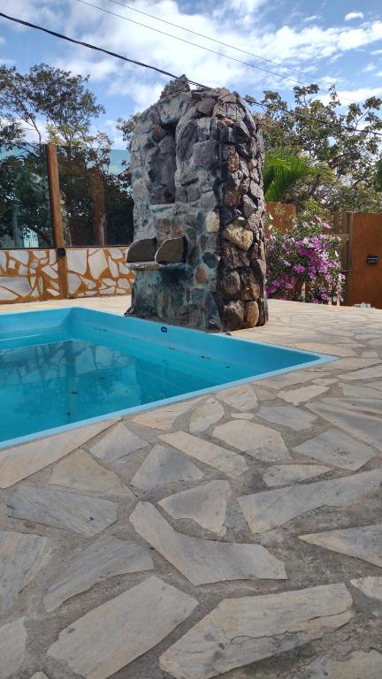 a swimming pool with a stone fireplace in a yard at Pousada Mangaba da Serra in Serra do Cipo