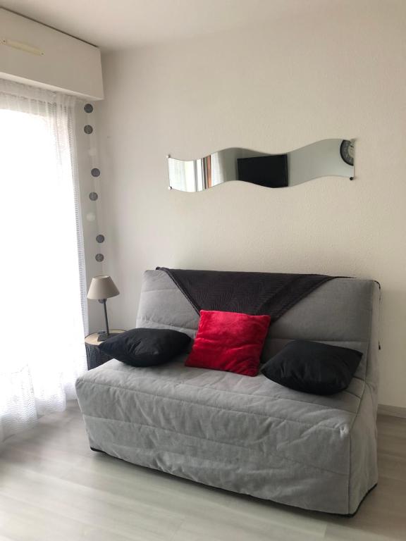 - une chambre avec un lit gris et un oreiller rouge dans l'établissement Jardin de la plage, à Villers-sur-Mer