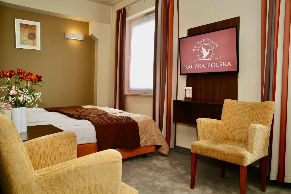 Hotel Tęczowy Młyn في كيلسي: غرفة فندقية بسرير وطاولة وكراسي